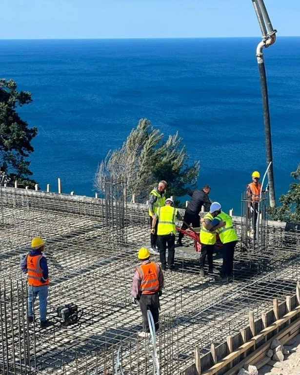 Workers on the reinforcement at the foundation laying, the sea behind